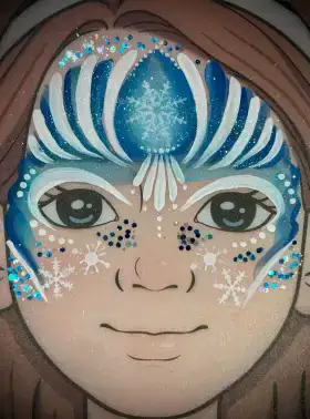 Blue snowflake crown face painting design with white sparkle accents across the forehead.
