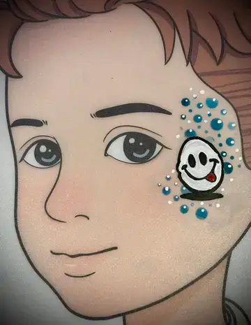 Smiling Easter egg face painting cheek design for family-friendly events.